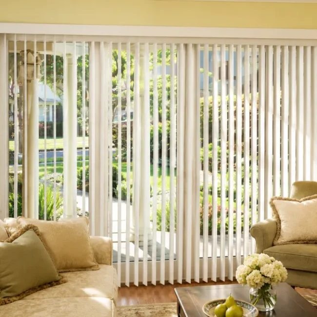 White vertical blinds covering a large living room patio door with natural light and modern home décor